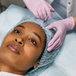 Close-up of a cosmetic procedure using injectables on a woman's forehead in a clinic setting.